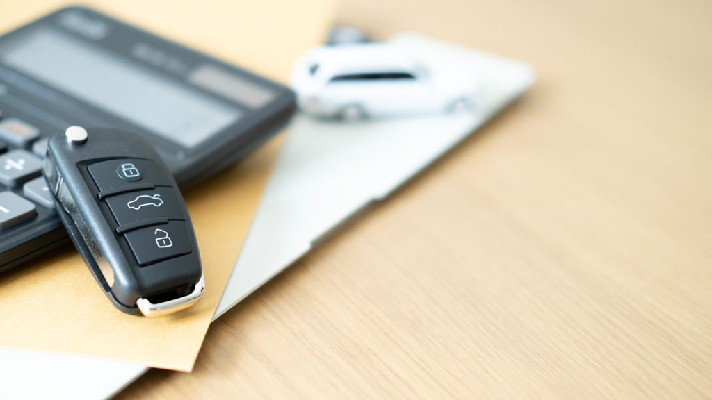 Clés de véhicule de société posées sur bureau avec écran affichant des données